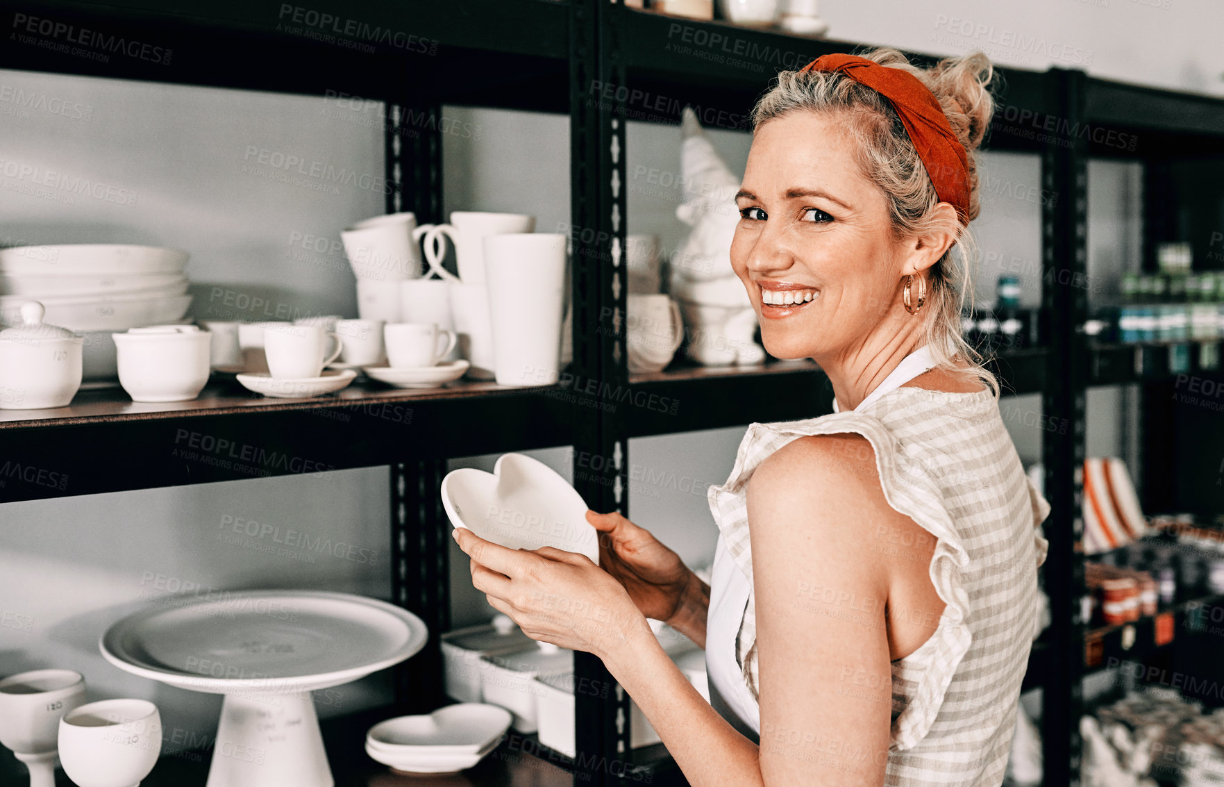 Buy stock photo Pottery, workshop and portrait of happy woman on shelf to arrange ceramic product for decoration. Display case, potter or person with creative art, craft or check stock of inventory in small business