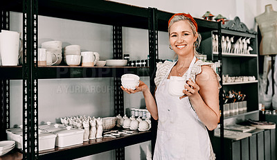 Buy stock photo Cropped portrait of an attractive mature woman standing and organising her pottery on a shelf in her workshop
