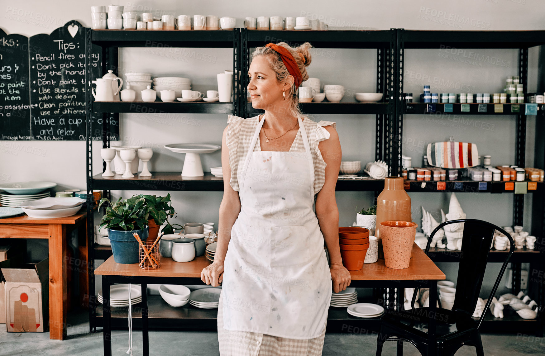 Buy stock photo Cropped shot of an attractive mature woman standing alone in her pottery workshop during the day