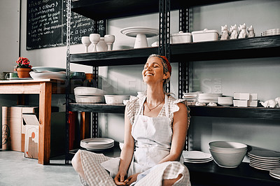 Buy stock photo Cropped shot of an attractive mature woman sitting contently on the floor alone in her pottery workshop