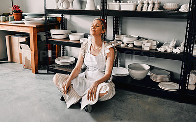 Buy stock photo Full length shot of an attractive mature woman sitting contently on the floor alone in her pottery workshop