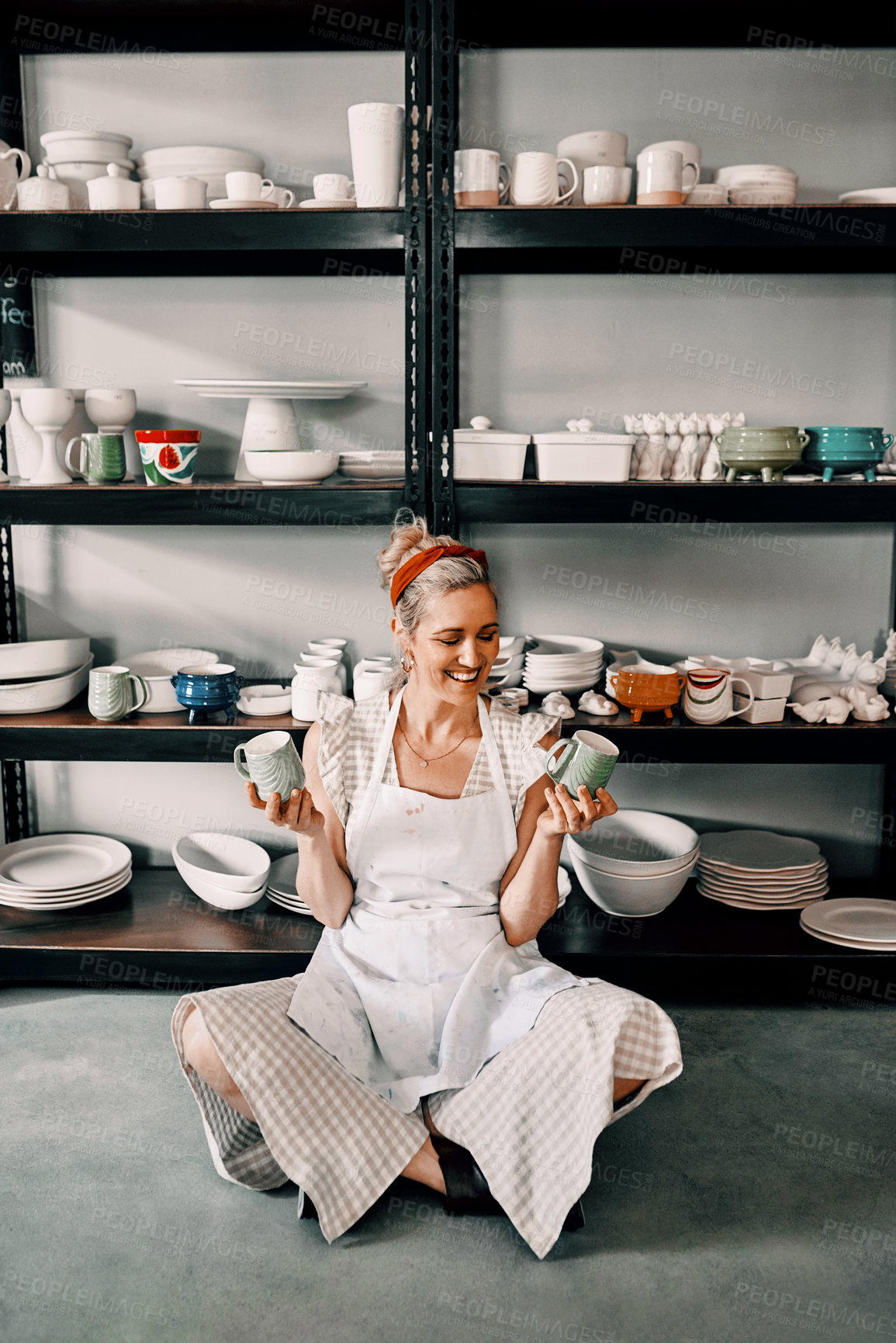 Buy stock photo Full length shot of an attractive mature woman sitting on the floor and holding her pottery in her workshop