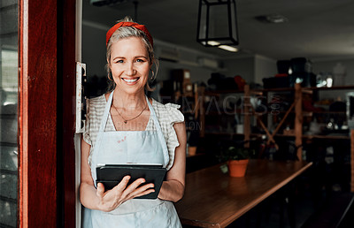 Buy stock photo Cropped portrait of an attractive mature woman standing alone and using a tablet in her pottery workshop