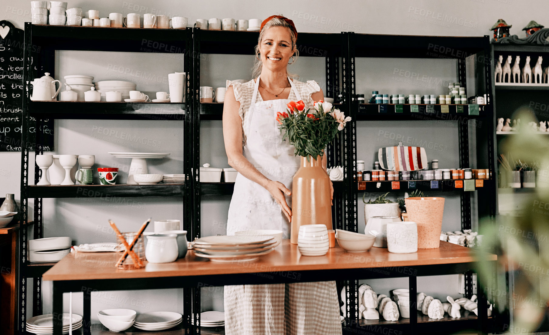 Buy stock photo Cropped portrait of an attractive mature woman standing alone and holding a handmade vase in her pottery workshop
