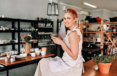 Buy stock photo Cropped portrait of an attractive mature woman sitting alone and holding a cup of coffee in her pottery workshop