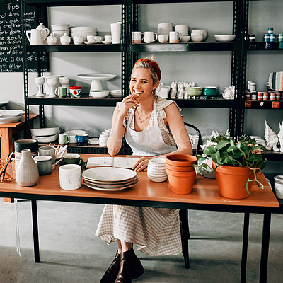 Buy stock photo Cropped portrait of an attractive mature woman sitting alone at her desk in her pottery workshop