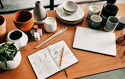 Buy stock photo High angle shot of a potter's sketches in a notebook and her laptop on a work desk in her workshop