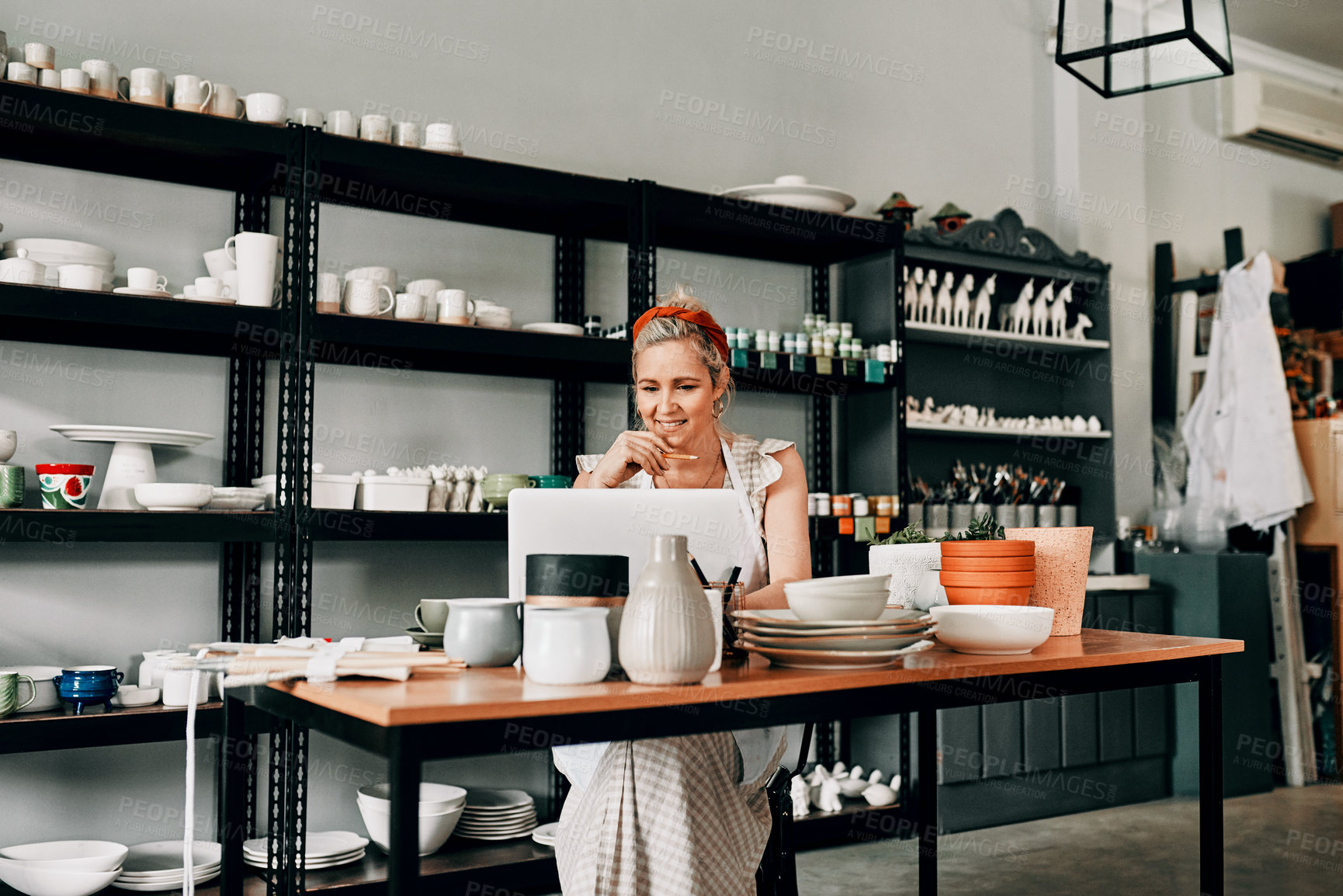 Buy stock photo Creative, pottery and woman sitting with laptop in workshop. Small business or startup, technology or social networking and female person in kitchen with art sculpture on the table or on desk