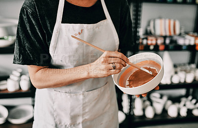 Buy stock photo Cropped shot of an unrecognizable woman standing alone and painting a pottery bowl in her workshop