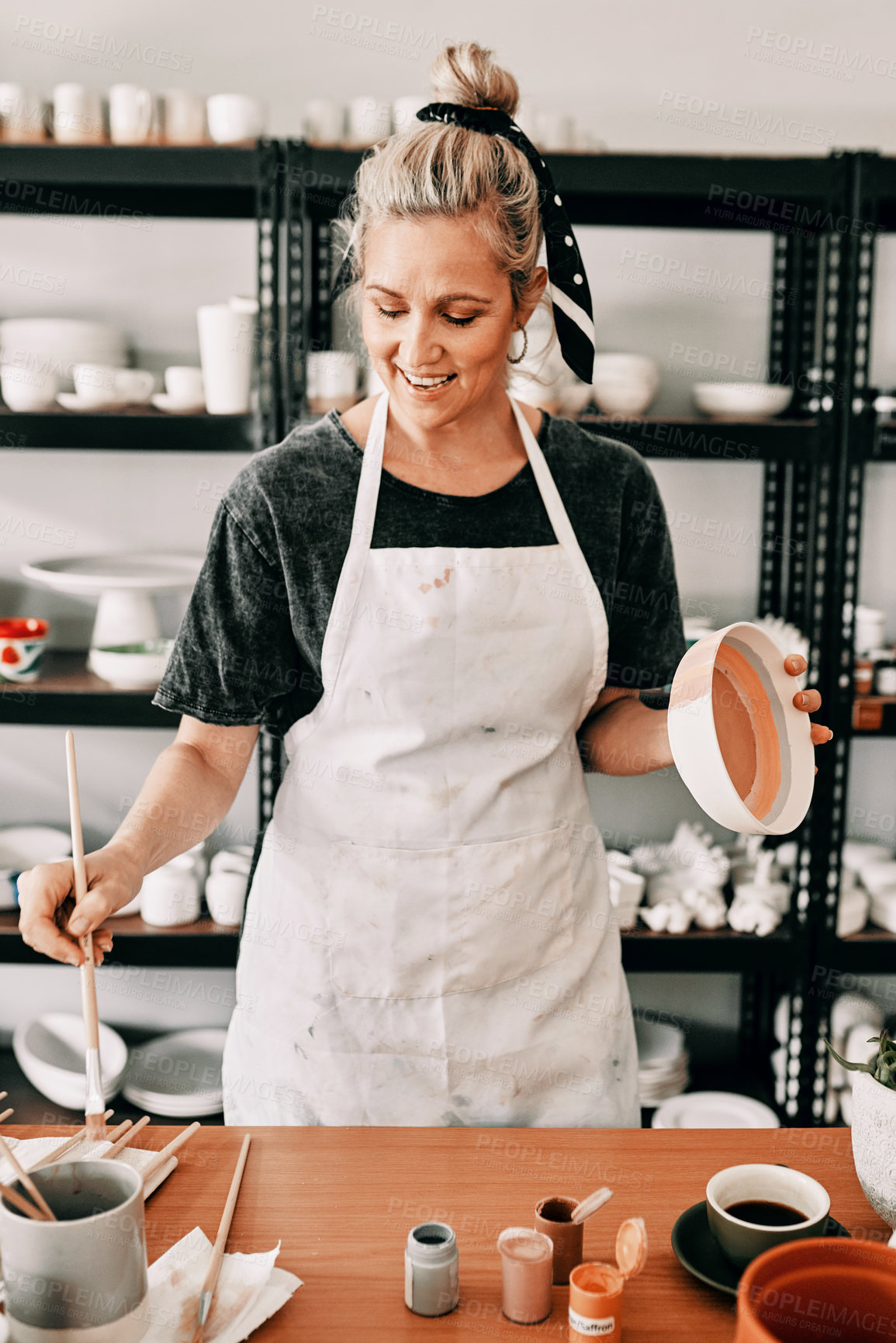 Buy stock photo Cropped shot of an attractive mature woman standing alone and painting a pottery bowl in her workshop