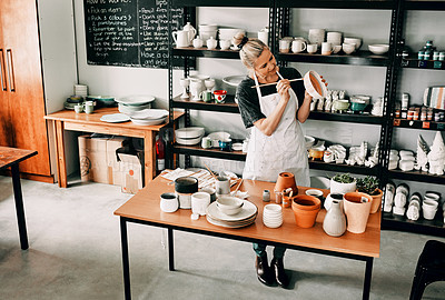 Buy stock photo Full length shot of an attractive mature woman standing alone and painting a pottery bowl in her workshop