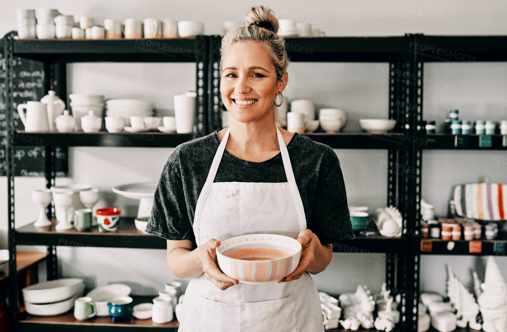 Buy stock photo Cropped portrait of an attractive mature woman standing alone and holding her finished pottery in her workshop
