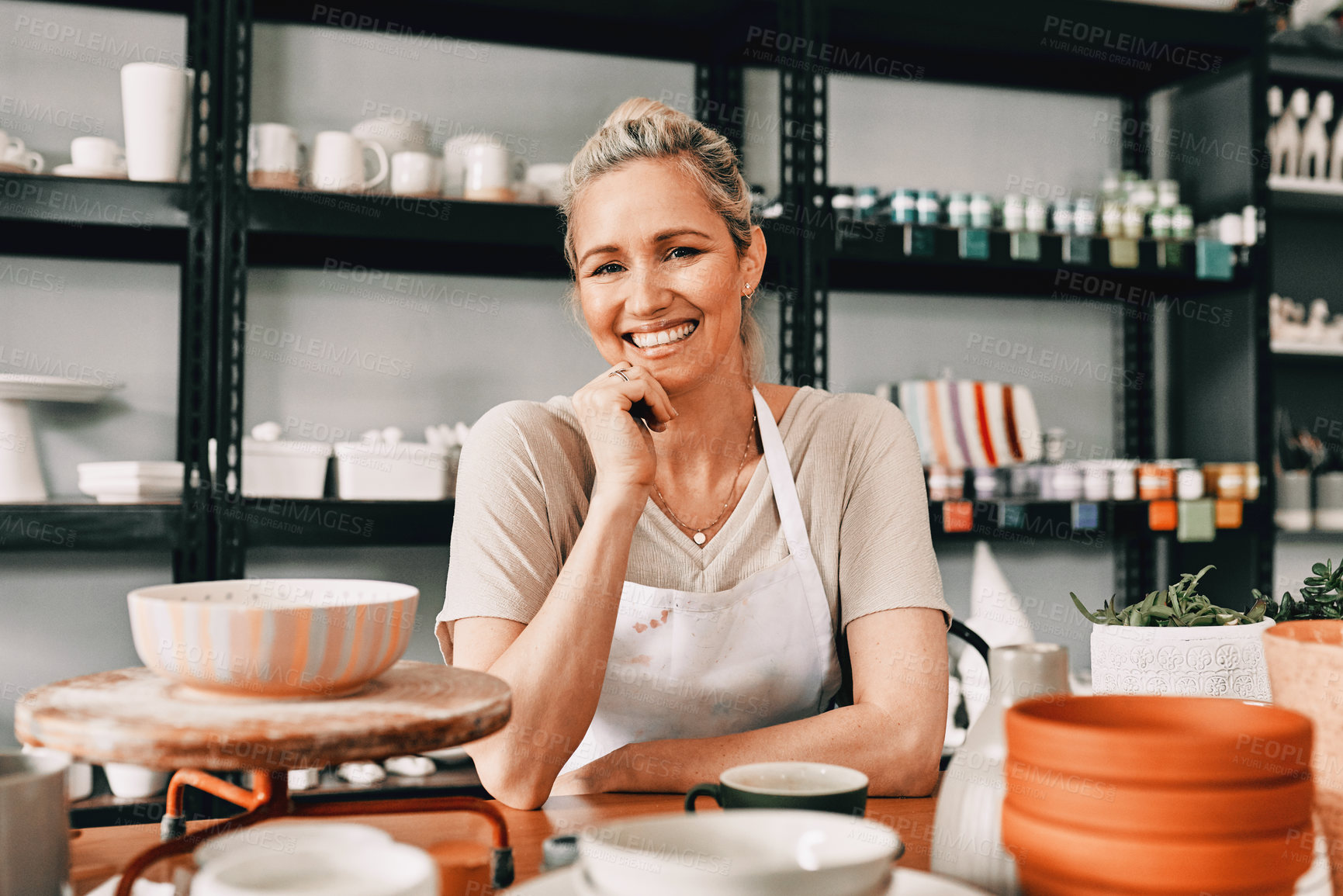Buy stock photo Cropped portrait of an attractive mature woman sitting alone with her hand on her chin in her pottery workshop