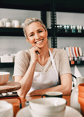 Buy stock photo Cropped portrait of an attractive mature woman sitting alone with her hand on her chin in her pottery workshop