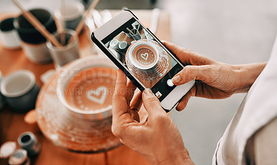 Buy stock photo Cropped shot of an unrecognizable woman standing and taking a picture of her pottery with her cellphone in her workshop