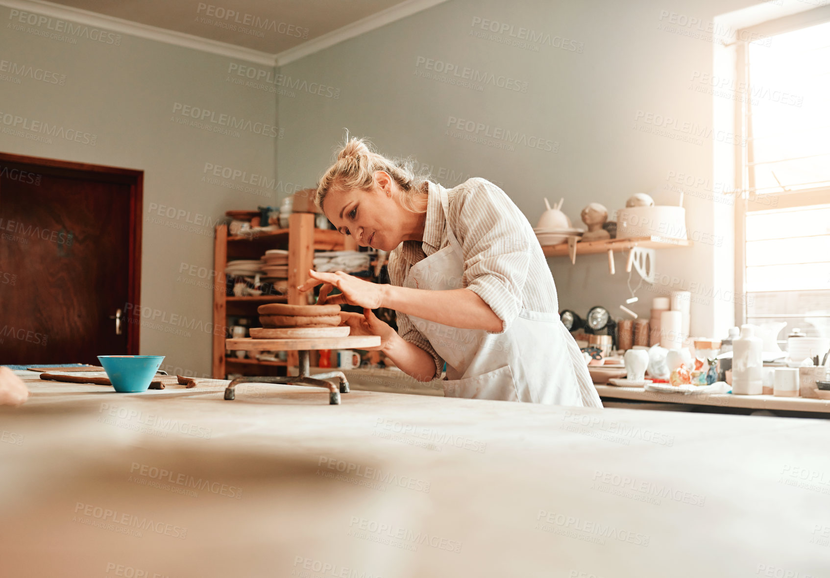 Buy stock photo Woman, clay and pottery wheel in factory for craft, tools or sustainable production at small business. Person, artist and entrepreneur for eco friendly material, sculpture or manufacturing in studio