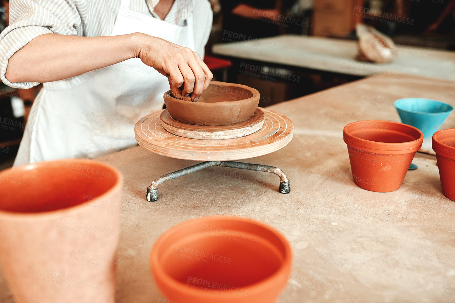 Buy stock photo Cropped shot of an unrecognizable woman shaping a clay pot in her workshop