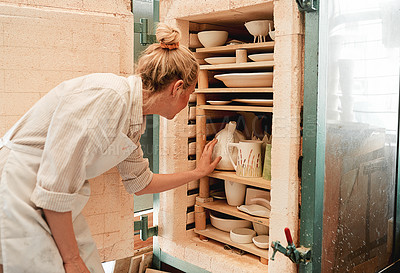 Buy stock photo Shot of a artisan placing earthenware in her kiln
