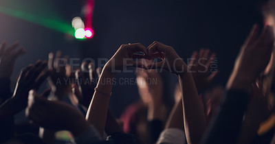 Buy stock photo Cropped shot of an unrecognizable young woman making a heart shape with her hands while dancing in a club