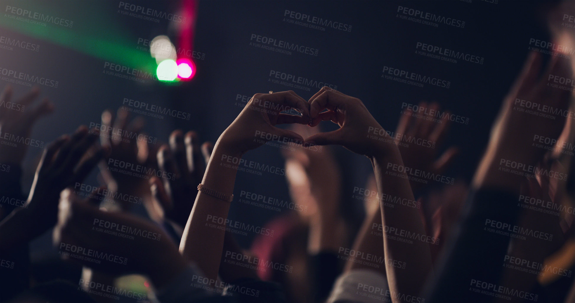 Buy stock photo Cropped shot of an unrecognizable young woman making a heart shape with her hands while dancing in a club