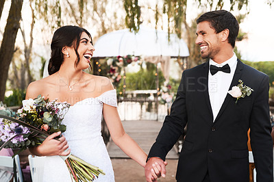 Buy stock photo Shot of a happy newlywed young couple holding hands together outdoors on their wedding day