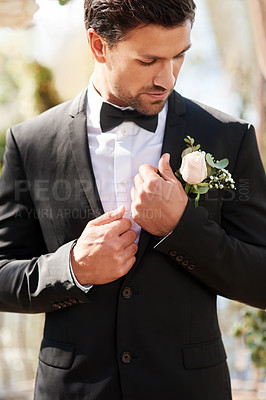 Buy stock photo Shot of a handsome young man fixing himself up and getting ready outdoors on his wedding day