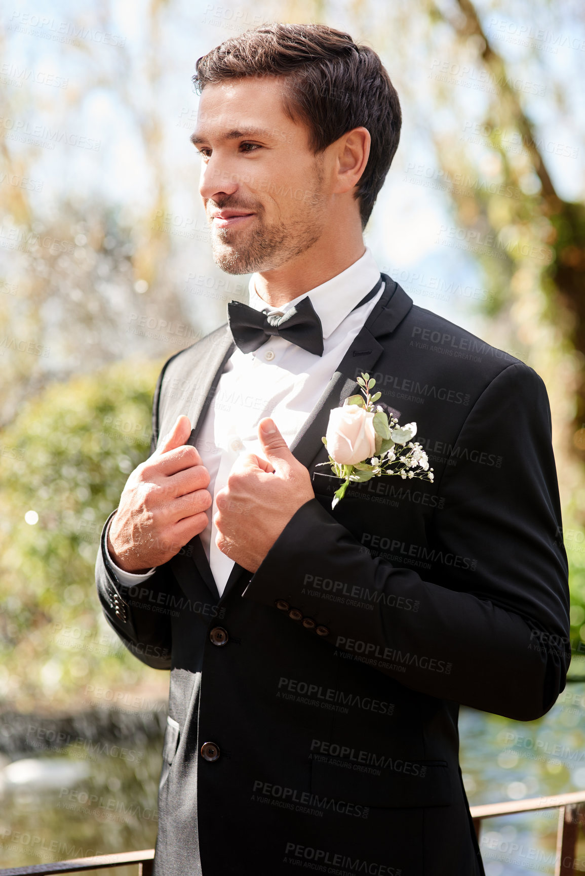 Buy stock photo Shot of a handsome young man fixing himself up and getting ready outdoors on his wedding day