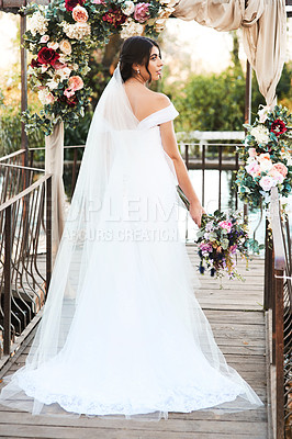 Buy stock photo Rearview shot a beautiful young bride standing outdoors on her wedding day