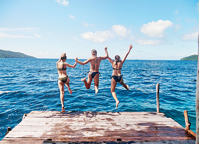 Buy stock photo Rearview shot of a group of young women jumping off a pier and into the ocean together