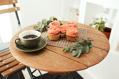 Buy stock photo Cropped shot of freshly baked cupcakes on a metal tray and a cup of coffee on a table indoors