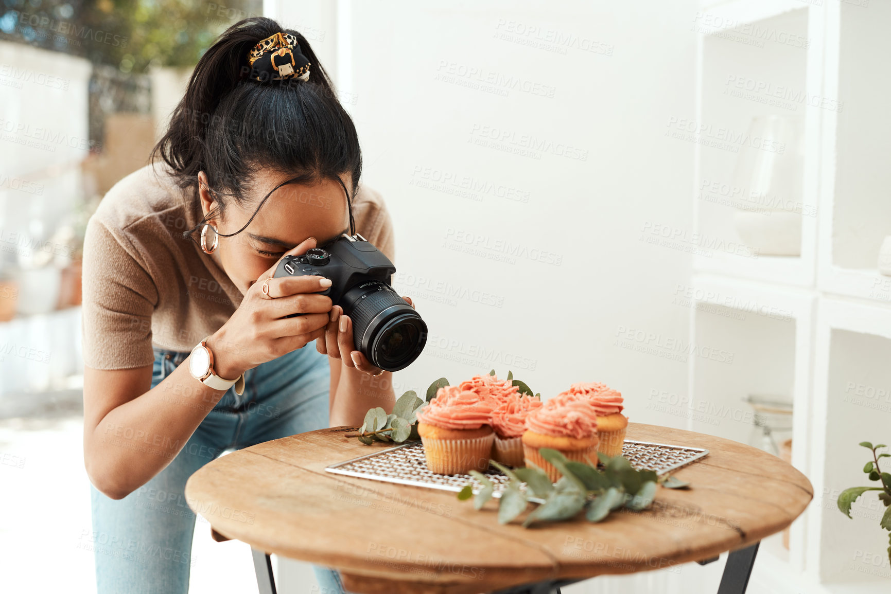 Buy stock photo Cropped shot of an attractive young businesswoman using her camera to photograph cupcakes for her blog