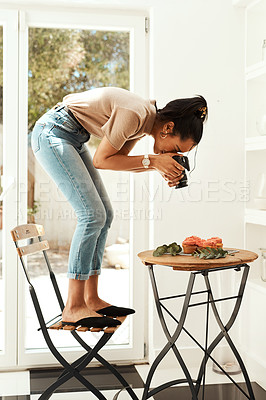 Buy stock photo Full length shot of an attractive young businesswoman standing and using her camera to photograph cupcakes for her blog
