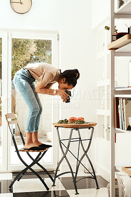 Buy stock photo Full length  shot of an attractive young businesswoman standing and using her camera to photograph cupcakes for her blog