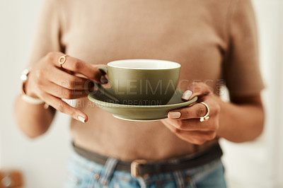 Buy stock photo Cropped shot of an unrecognizable woman standing alone in her home and holding a cup of coffee