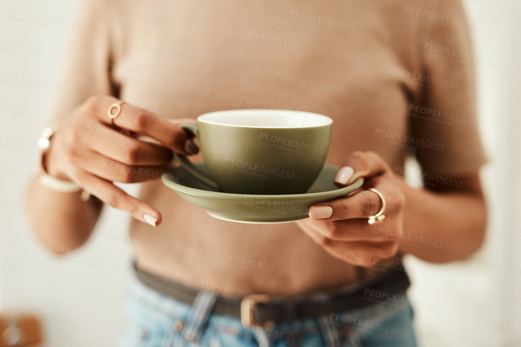 Buy stock photo Cropped shot of an unrecognizable woman standing alone in her home and holding a cup of coffee
