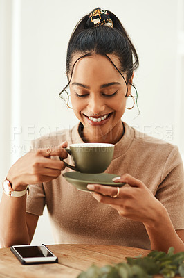 Buy stock photo Cropped shot of an attractive young woman sitting alone in her home and enjoying a cup of coffee