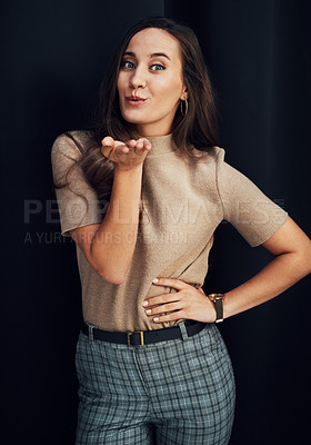 Buy stock photo Fashion, beauty and woman blowing a kiss in studio on a dark background for love, romance or dating. Hand, portrait and smile with a happy young female standing indoors against a black wall alone