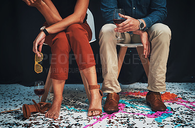 Buy stock photo Party, feet and event with a man and woman in studio on a dark background after a new year celebration together. Wine, fashion and confetti with a male and female sitting on a chair on black backdrop