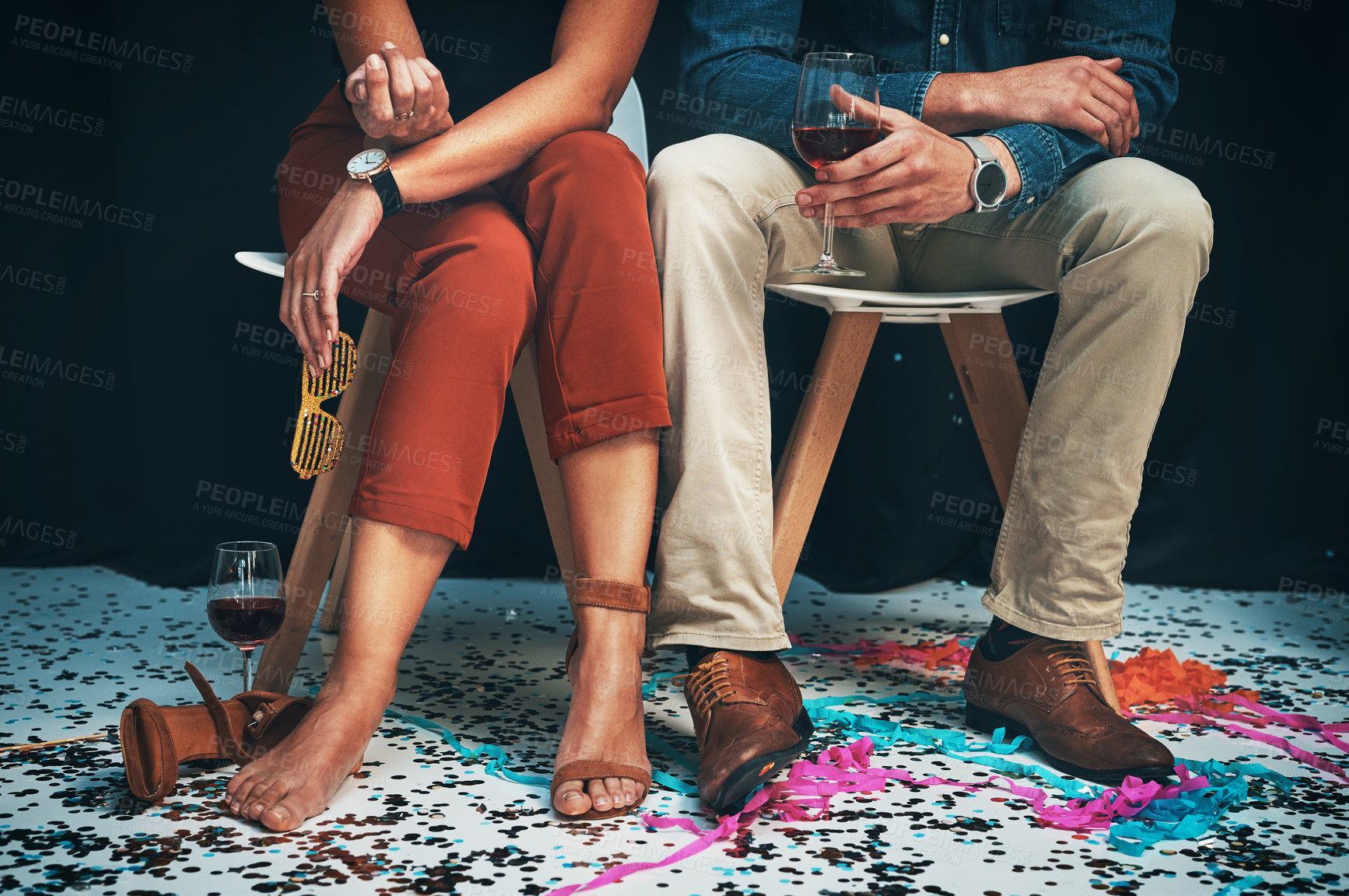 Buy stock photo Feet, man and woman sitting at a party to celebrate new years eve and socialise together. Legs, couple and celebrating while partying together at a festive celebration or event with confetti 
