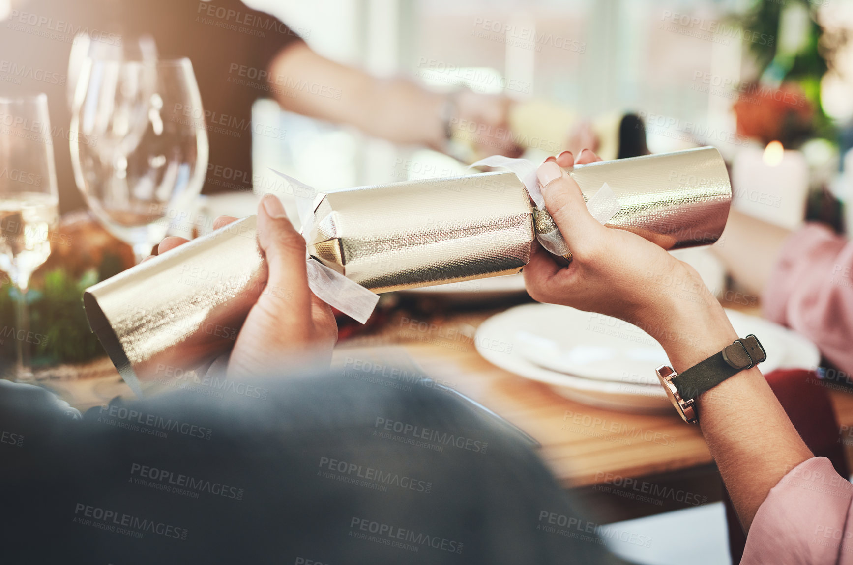 Buy stock photo Cropped shot of a group of unrecognizable people pulling crackers while dining together at Christmas