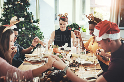 Buy stock photo Cropped shot of a group of young friends saying grace while dining together at Christmas