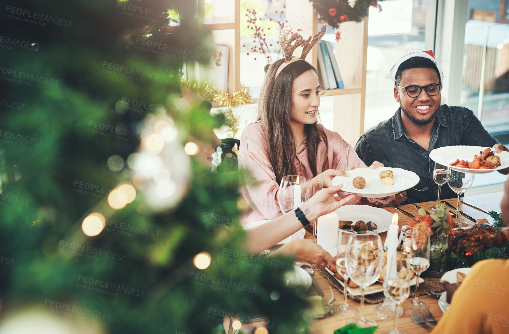 Buy stock photo Cropped shot of a group of cheerful young friends having Christmas lunch together at home