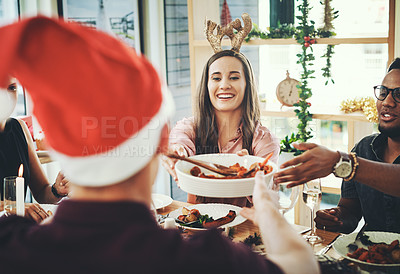 Buy stock photo Cropped shot of a group of cheerful young friends having Christmas lunch together at home
