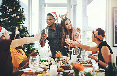 Buy stock photo Cropped shot of a cheerful young couple toasting with their friends while having Christmas lunch at home