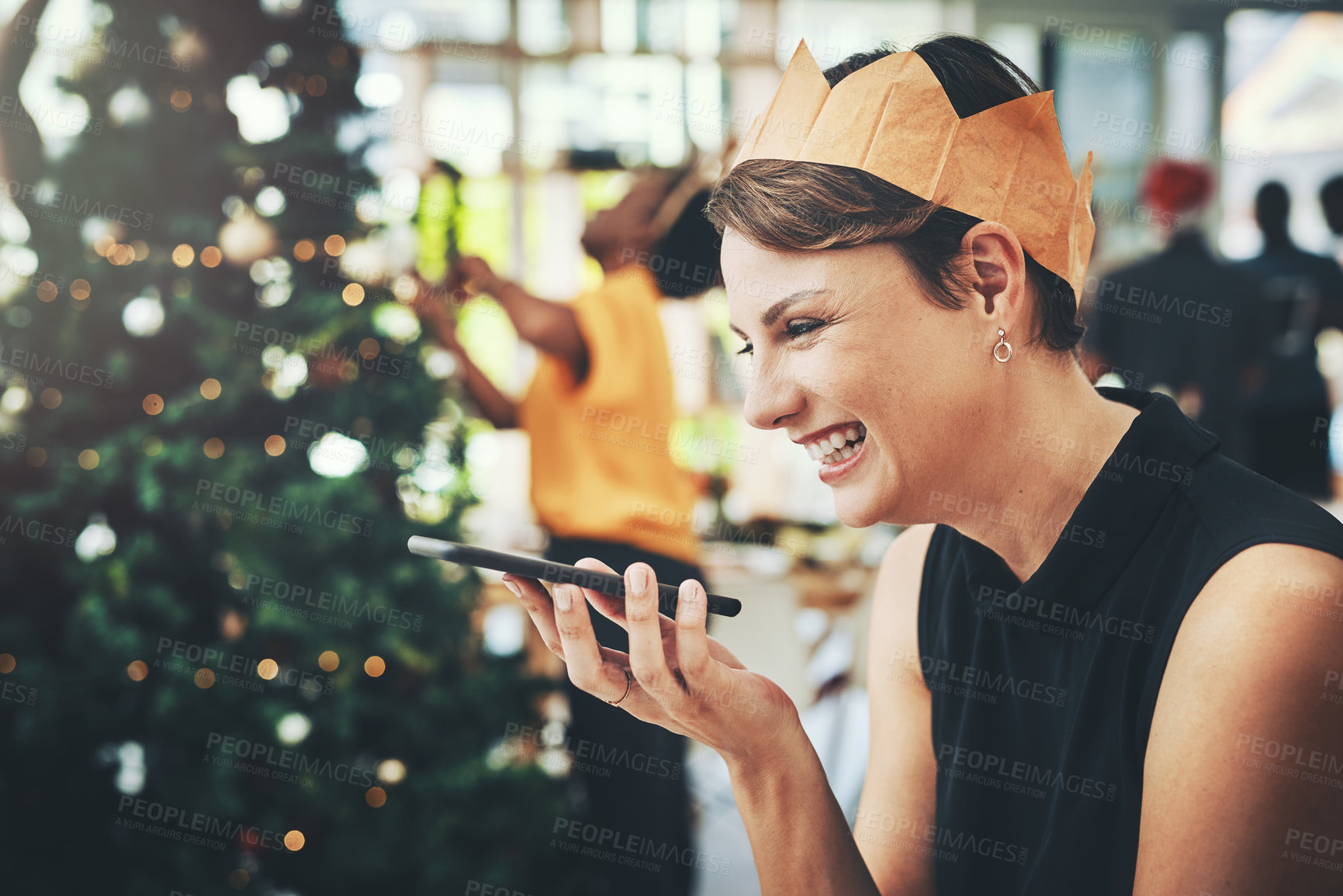 Buy stock photo Cropped shot of an attractive young woman taking a phonecall on Christmas day with her friends in the background