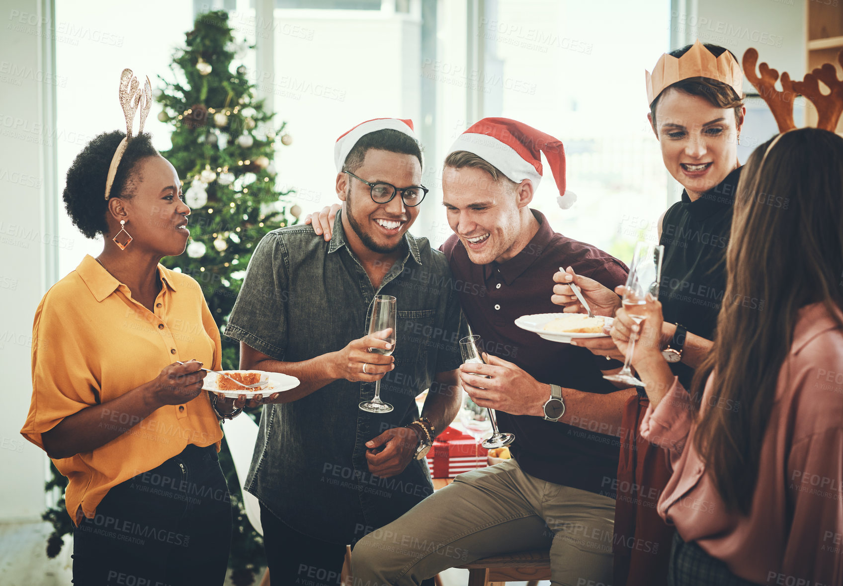 Buy stock photo Cropped shot of a group of cheerful young friends having cake and drinks together on Christmas day at home