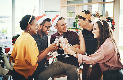 Buy stock photo Cropped shot of a group of cheerful young friends making a toast while celebrating Christmas together at home