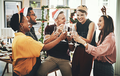 Buy stock photo Cropped shot of a group of cheerful young friends making a toast while celebrating Christmas together at home