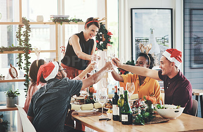 Buy stock photo Cropped shot of a group of cheerful young friends making a toast while having lunch together on Christmas day at home