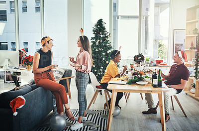 Buy stock photo Full length shot of a group of cheerful young people having chats with each other while celebrating Christmas together at home